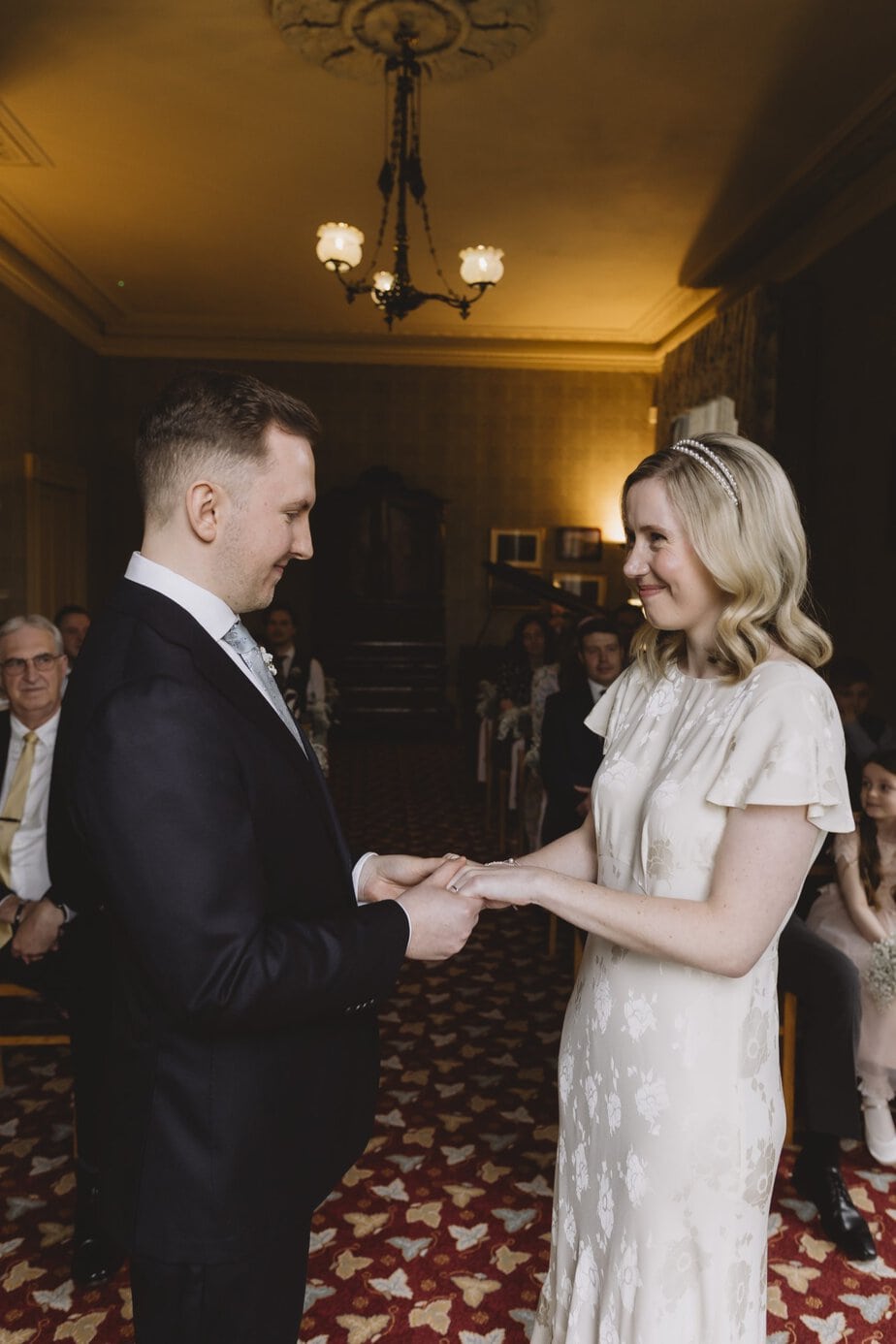 Couple holding hands and smiling during wedding ceremony at Didsbury House Hotel.